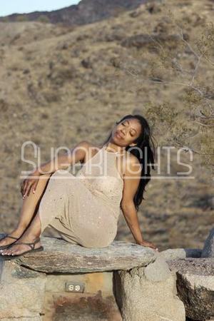 Iris Phoenix escort in beige dress posing outdoors in desert setting
